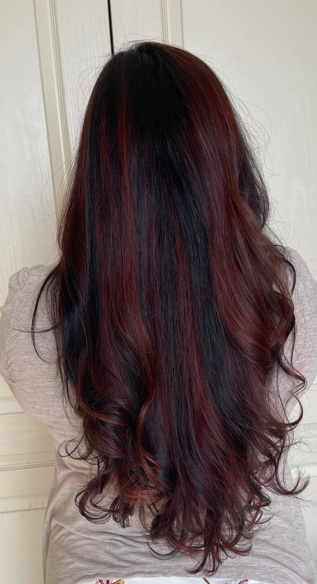 The back of a woman 's head with long dark red hair.