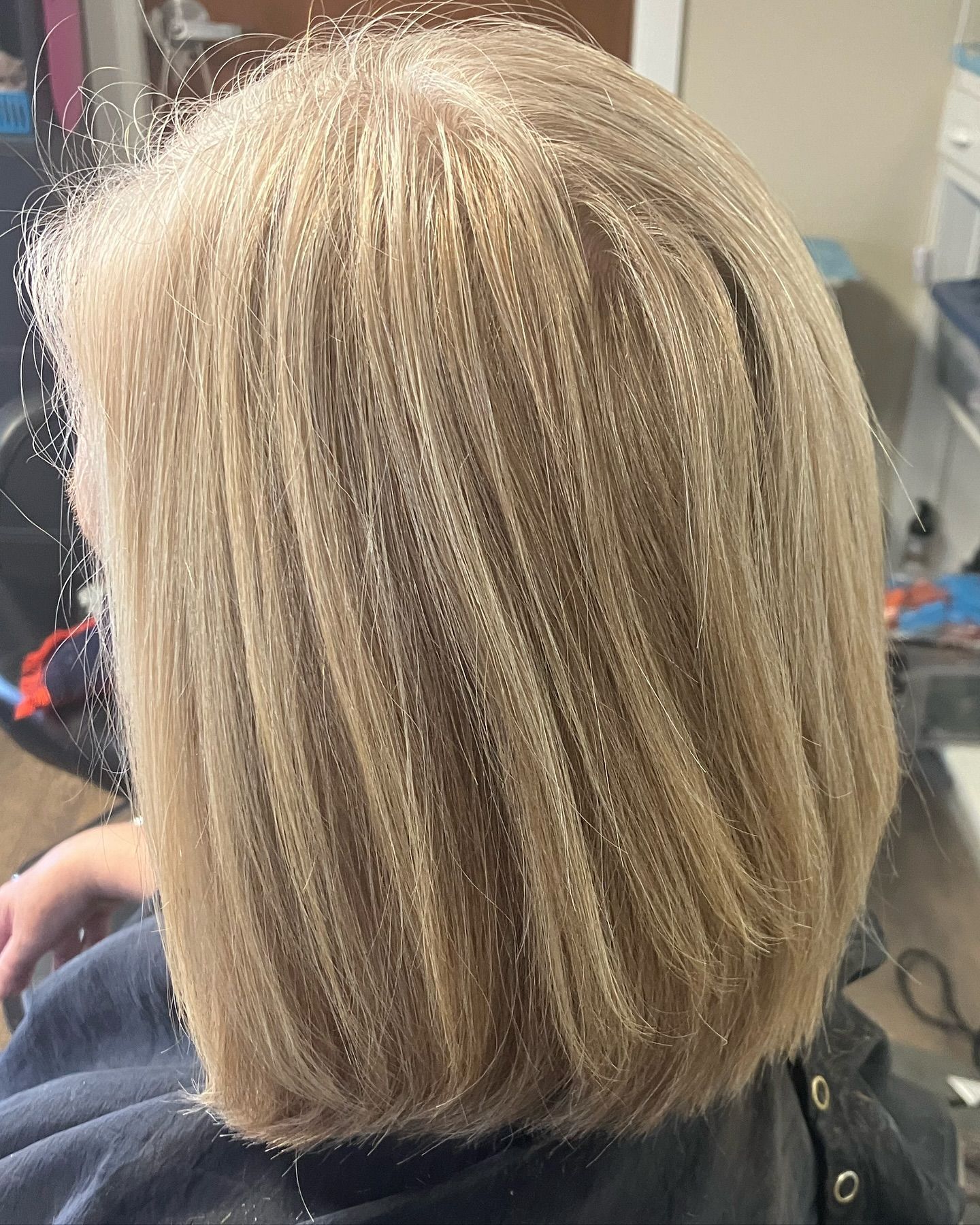 A woman with blonde hair is sitting in a chair in a salon.