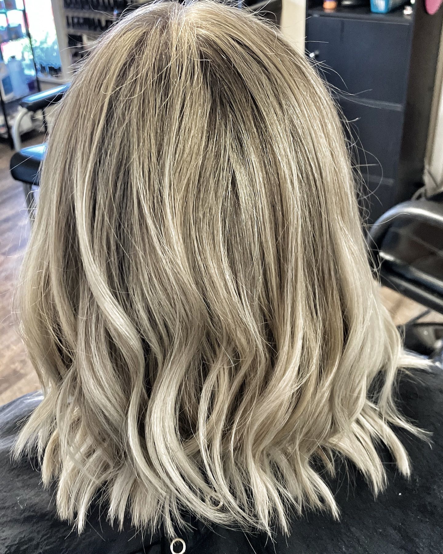A woman with blonde hair is sitting in a chair in a salon.