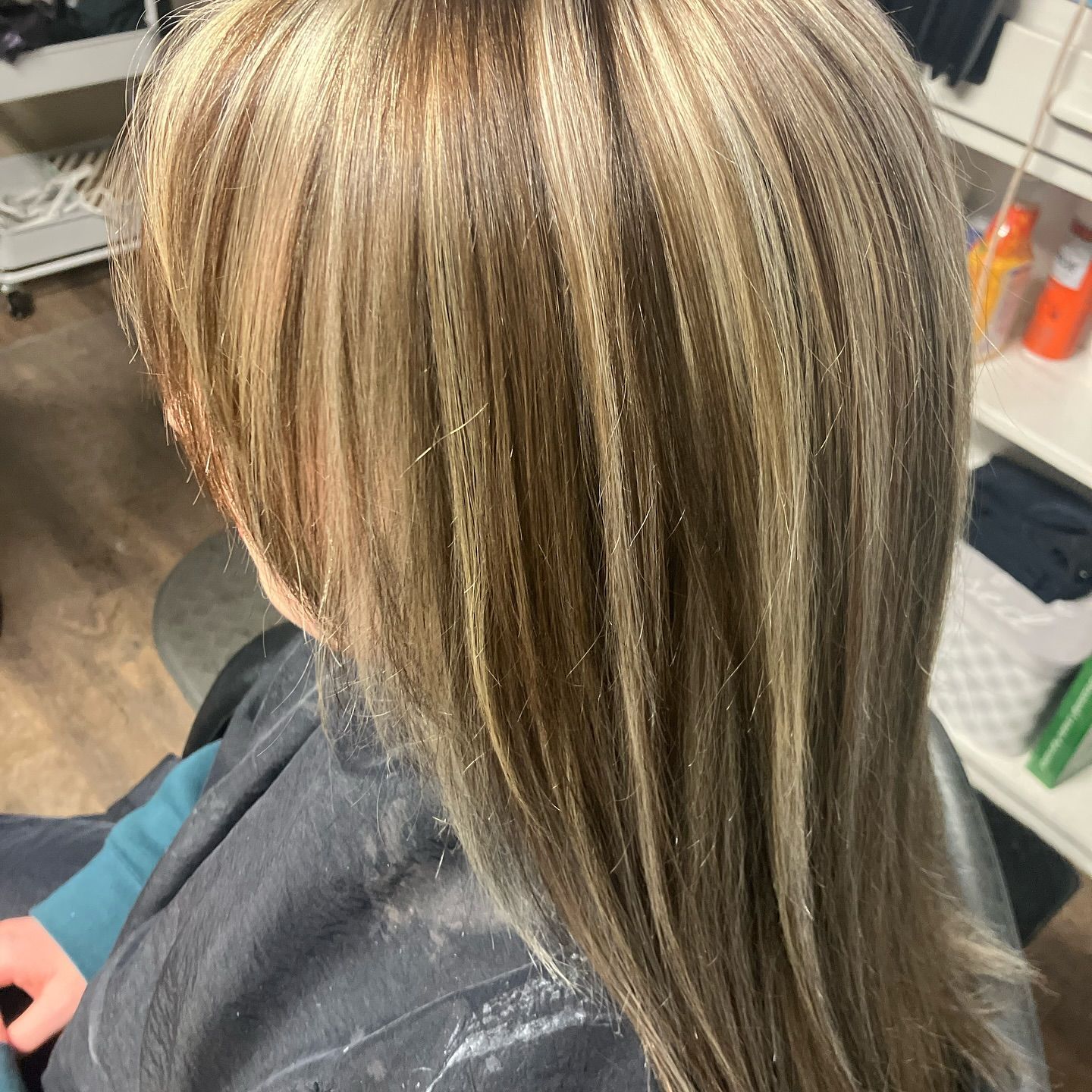 A woman with long blonde hair is sitting in a chair.