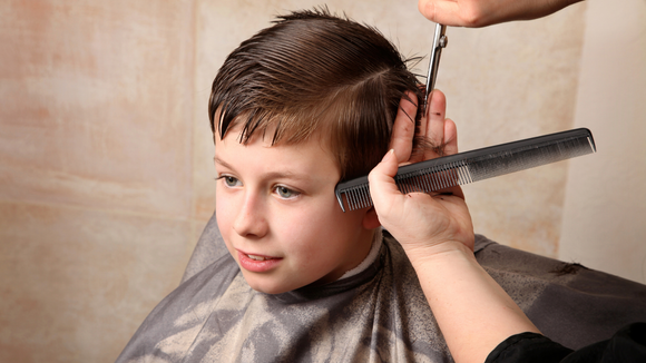 A young boy is getting his hair cut by a barber.