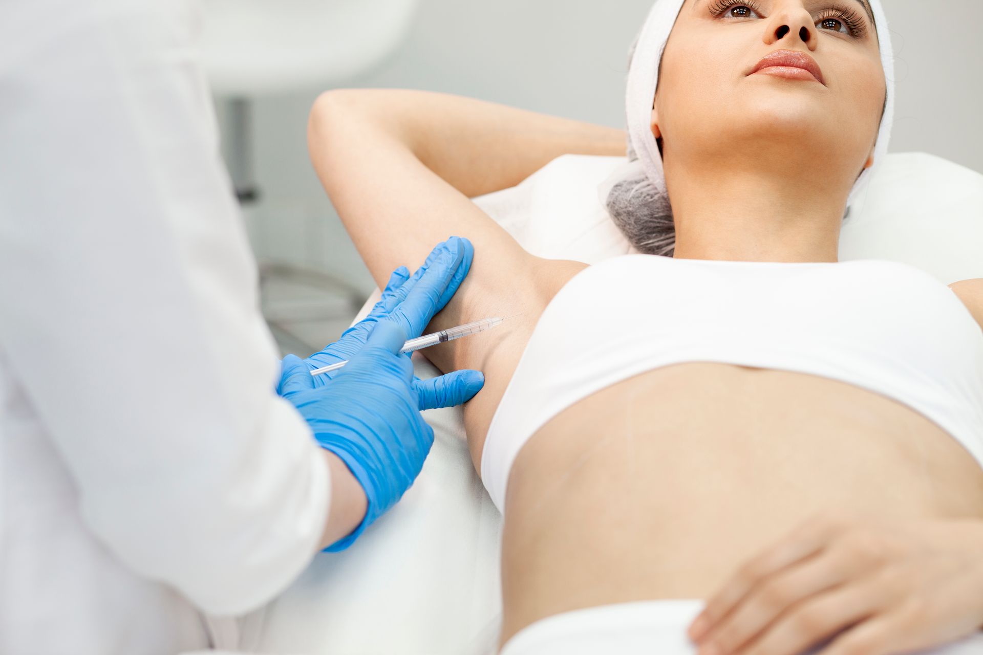 Person receiving injection in armpit by gloved medical professional.
