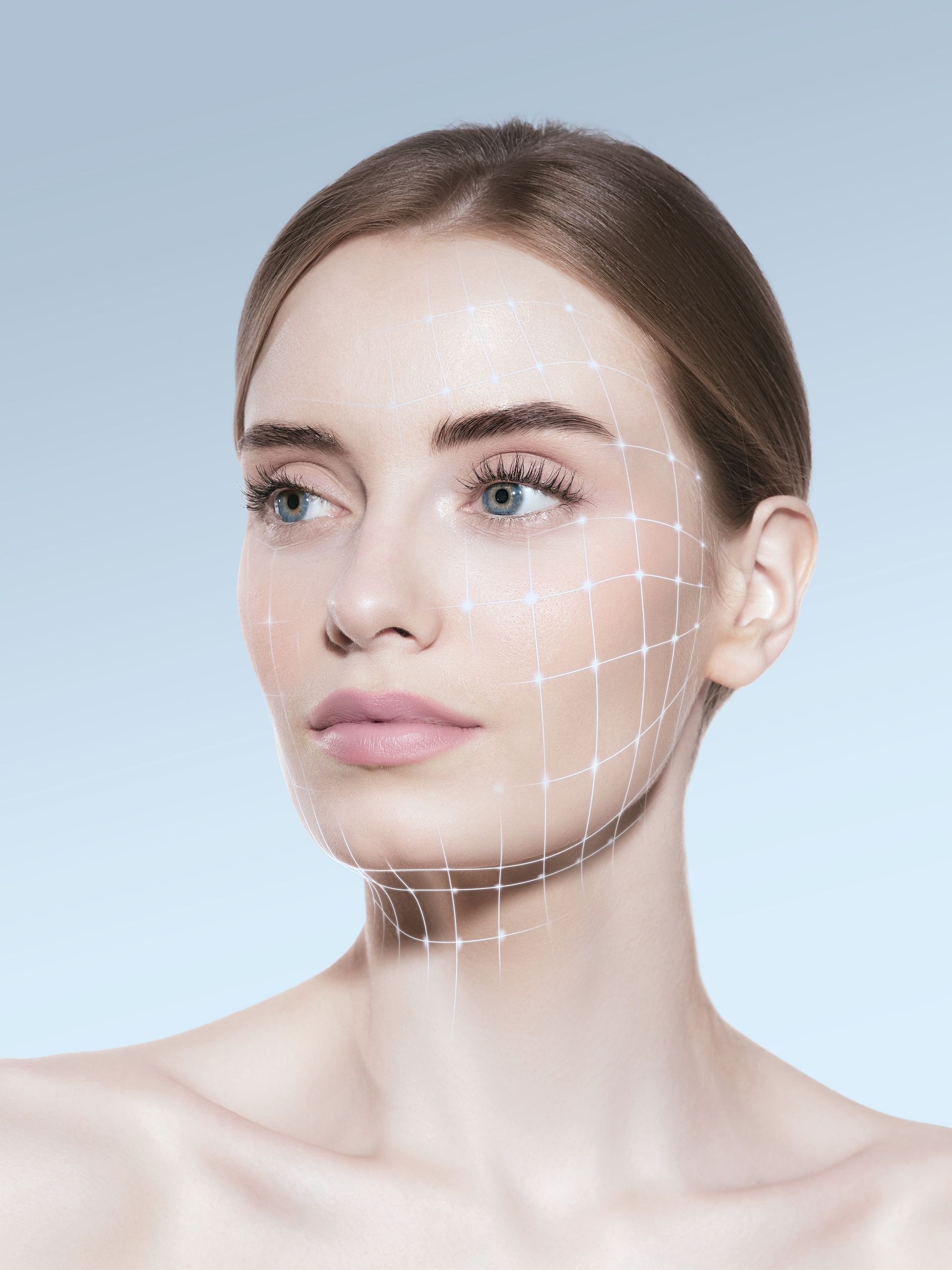 A person with white grid lines drawn on one side of their face and neck against a light blue background.