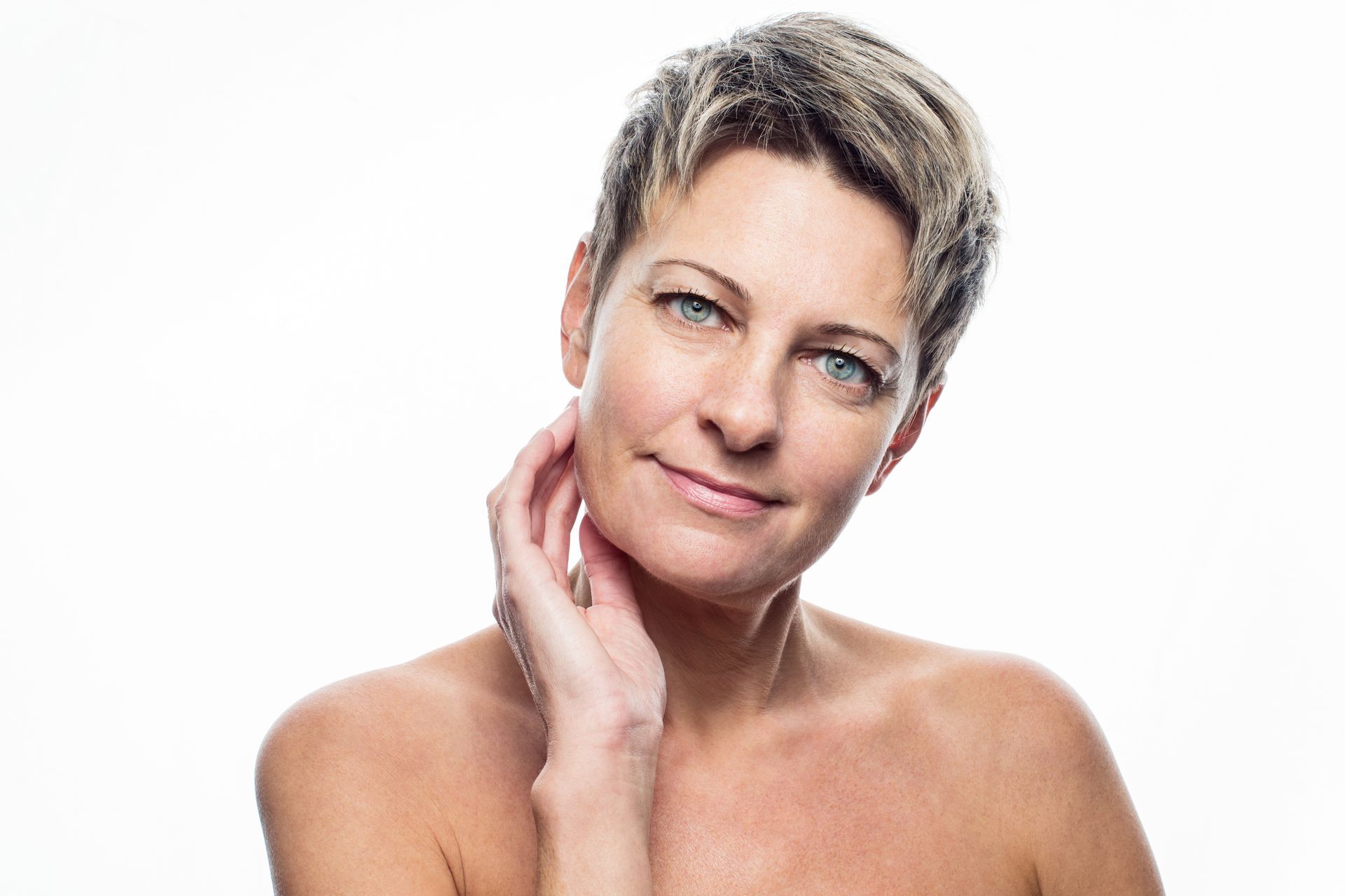 Woman touching her face, appearing concerned. Indoors, neutral background.