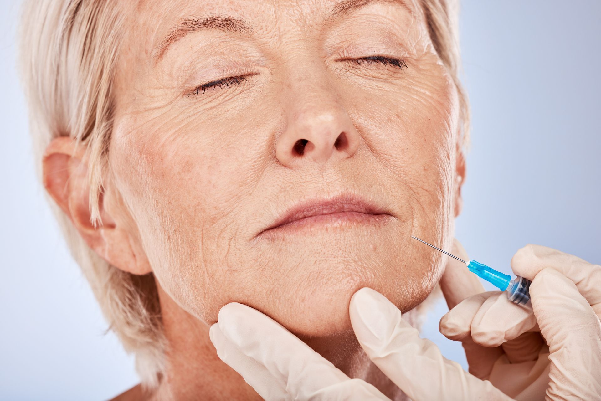 An older woman is getting a botox injection in her face.