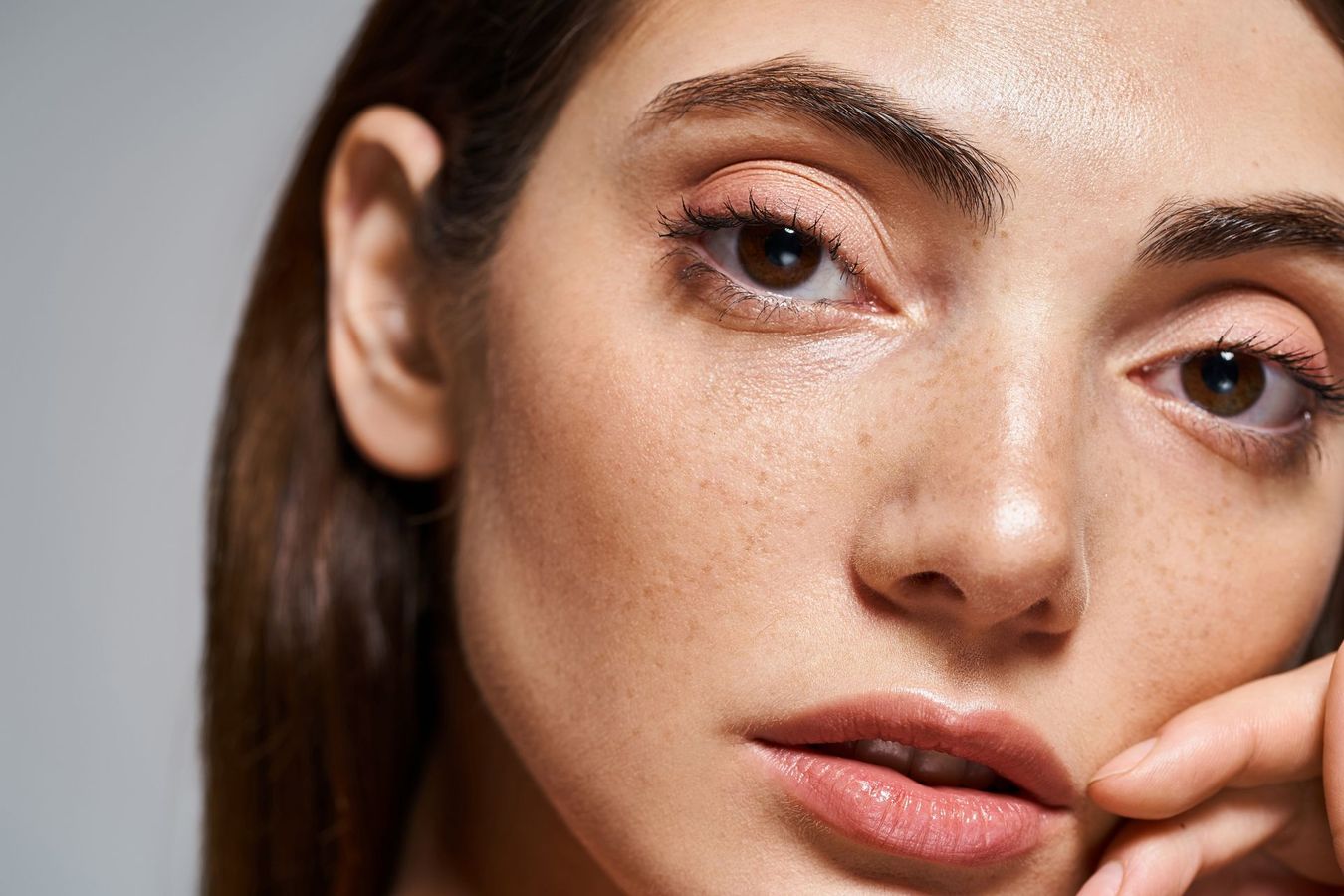 A close up of a woman 's face with her hand on her face.