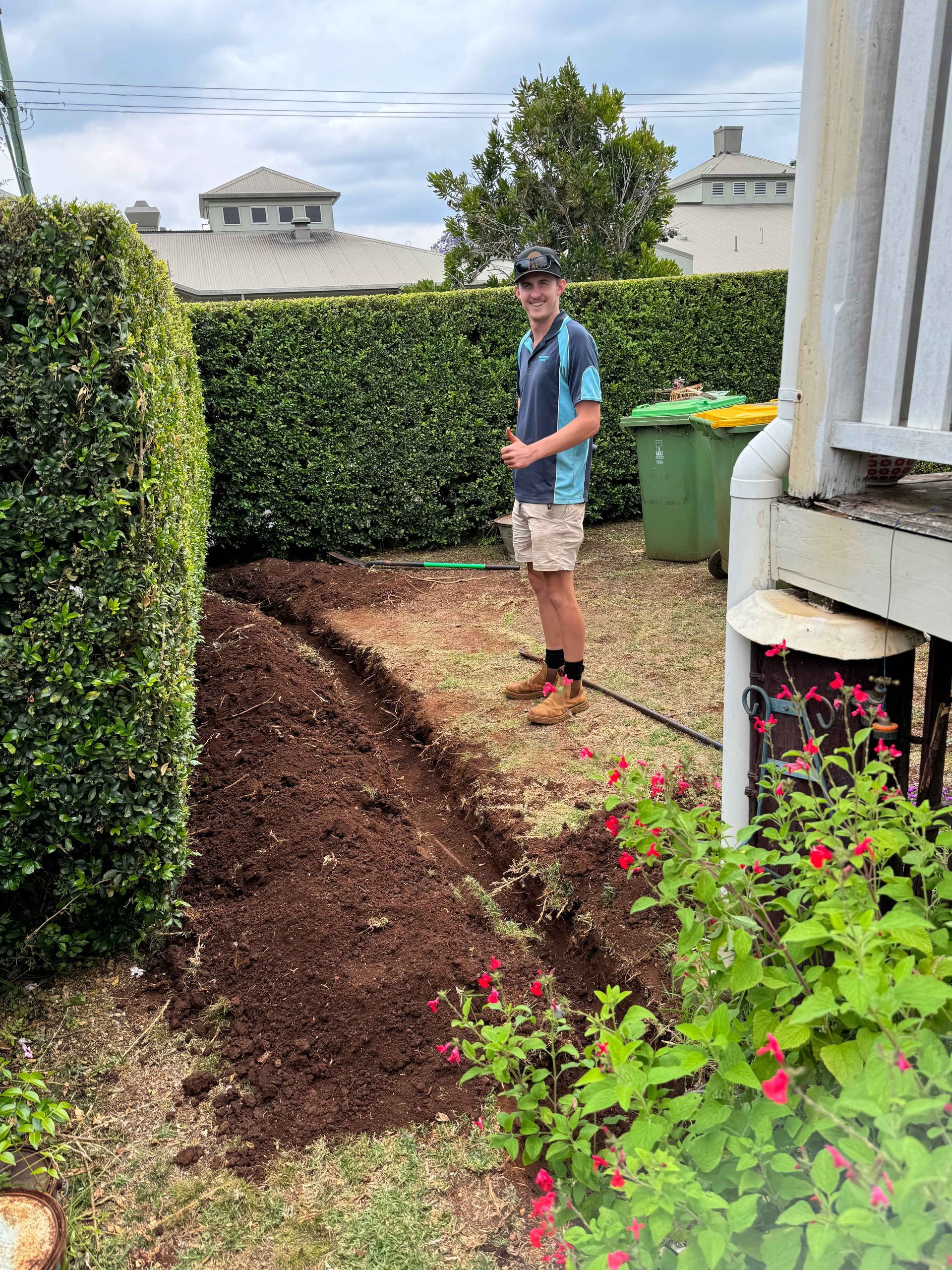 A man is standing next to a pile of dirt in a garden.