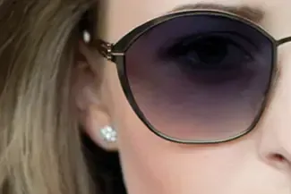 A close up of a woman wearing sunglasses and earrings.