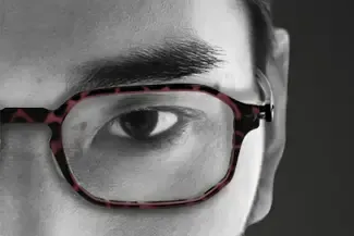 A close up of a man wearing glasses in a black and white photo.