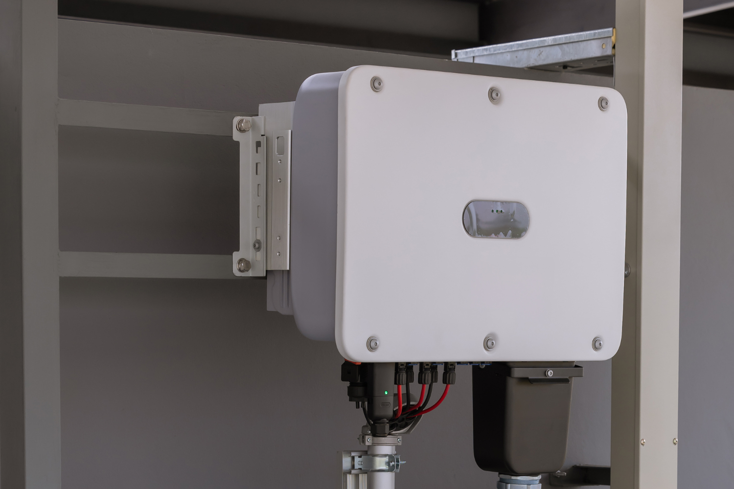 White solar panel inverter mounted on a metal frame, with wiring visible.