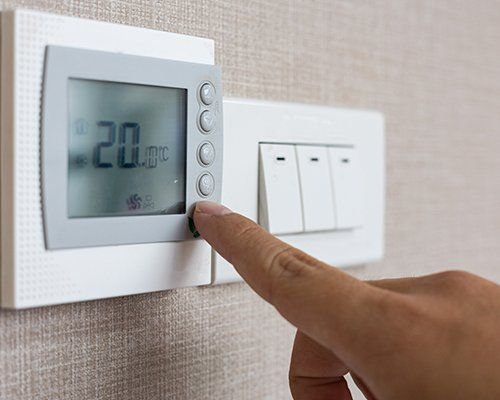 Man Adjusting a Thermostat — Greenwood, SC — Hughes Heating & Cooling