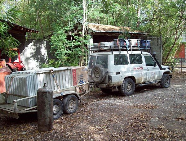 A white suv with a trailer attached to it is parked in front of a building.