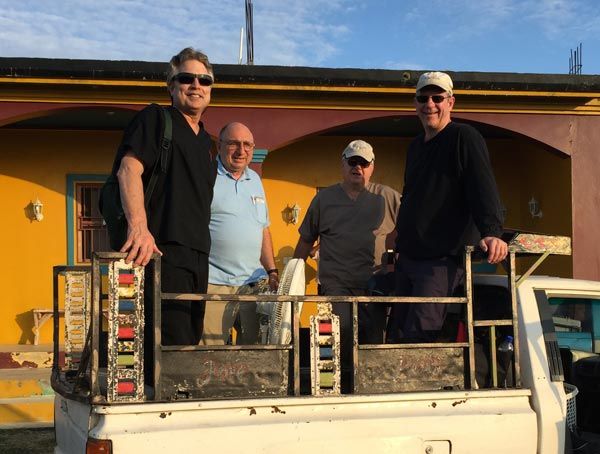 Three men are standing in the back of a truck.