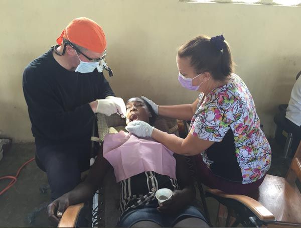 A man and a woman are examining a woman 's teeth.