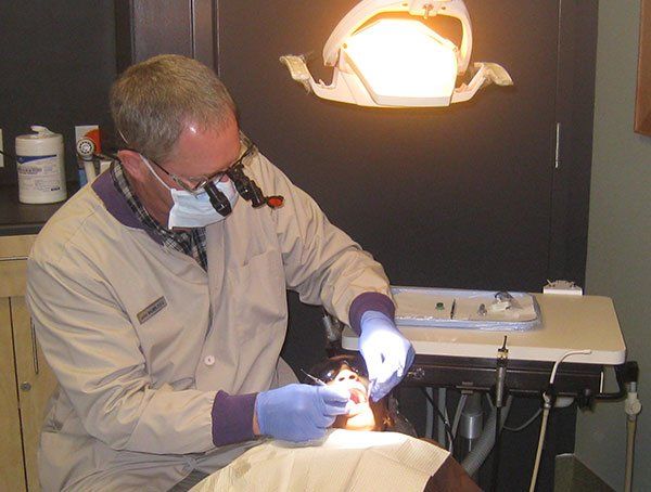 A dentist examines a patient 's teeth under a light