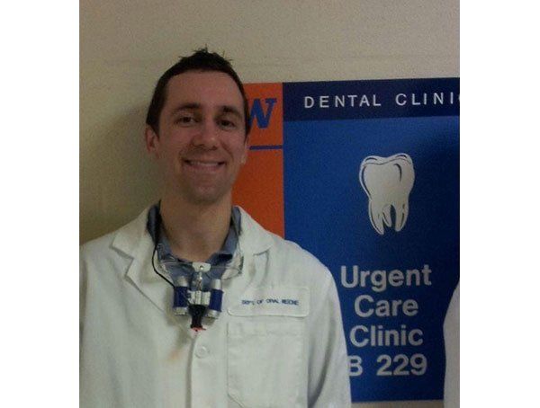 A man stands in front of a dental clinic sign