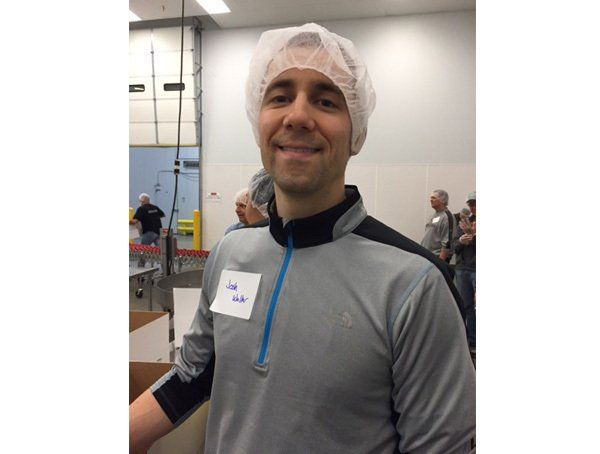 A man wearing a white hair net and a name tag