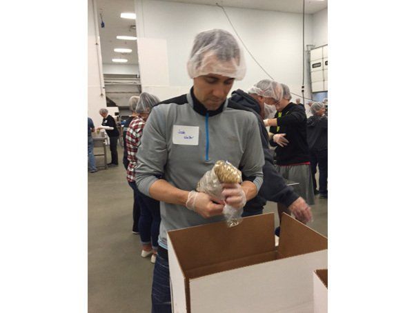 A man is holding a bag of food in a cardboard box.