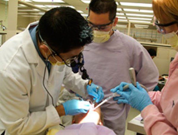 A group of dentists are working on a patient 's teeth