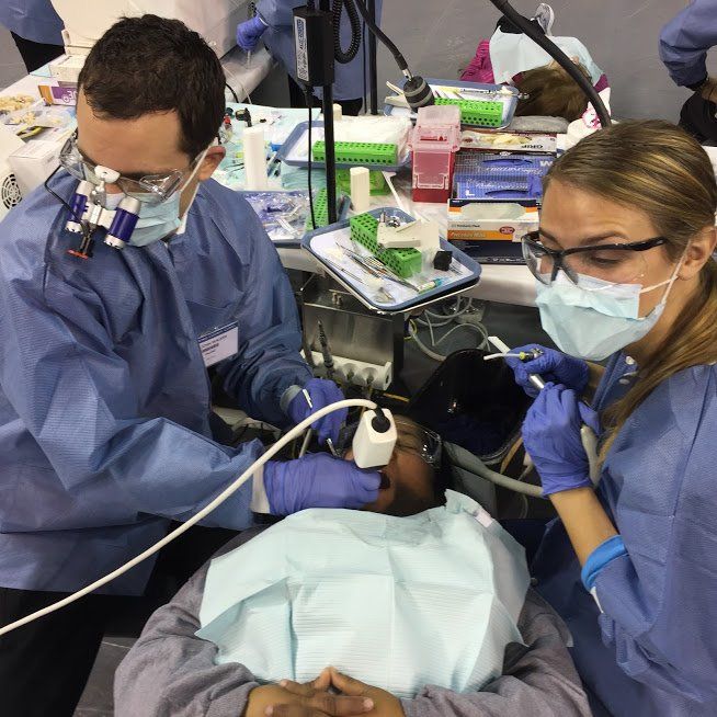 A man and a woman are working on a patient 's teeth