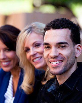 A man and two women are smiling for the camera