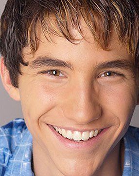 A young man in a blue shirt is smiling for the camera