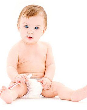 A baby in a diaper is sitting on the floor holding a toothbrush.