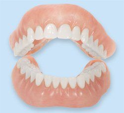 A close up of a denture with white teeth on a blue background.