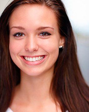 A woman with long brown hair is smiling for the camera.