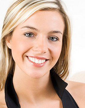 A woman with blonde hair is smiling and wearing a black top.