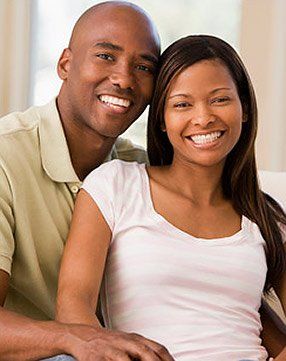 A man and a woman are sitting next to each other on a couch and smiling.