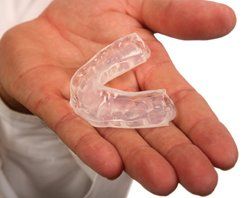 A person is holding a clear mouth guard in their hand.