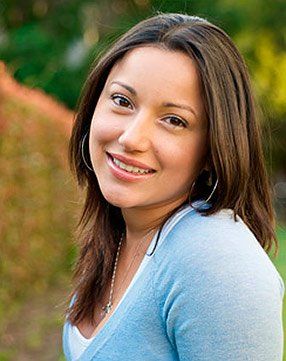 A woman in a blue sweater is smiling for the camera.
