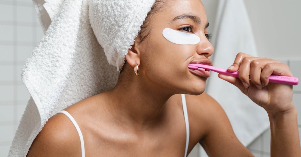 A woman with a towel wrapped around her head is brushing her teeth in the bathroom.