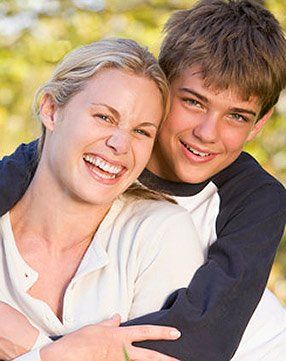 A boy and a woman are hugging each other and smiling.