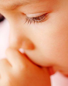 A close up of a child 's face with a hand on it.