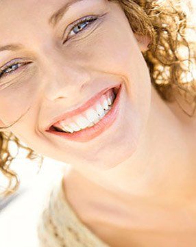 A close up of a woman 's face with curly hair smiling.