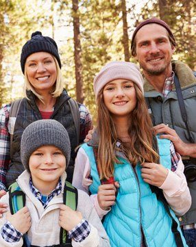 A family is posing for a picture in the woods.