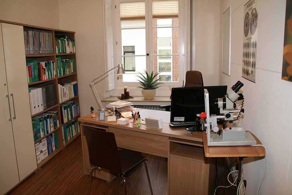 Ein Schreibtisch mit einem Computer und einem Mikroskop in einem Raum