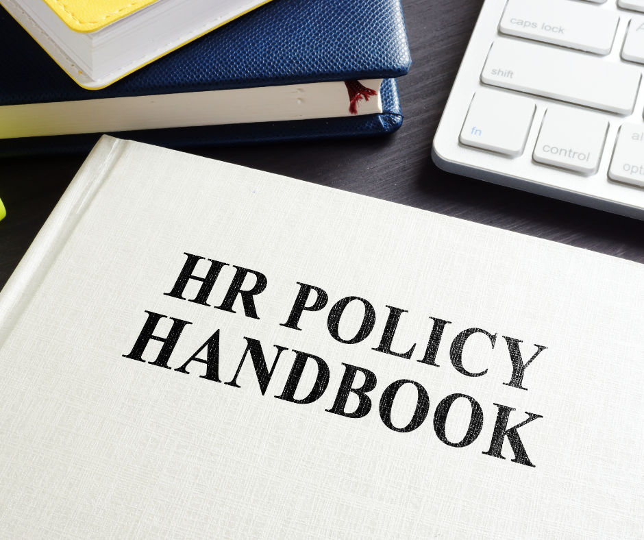 A hr policy handbook is sitting on a desk next to a keyboard