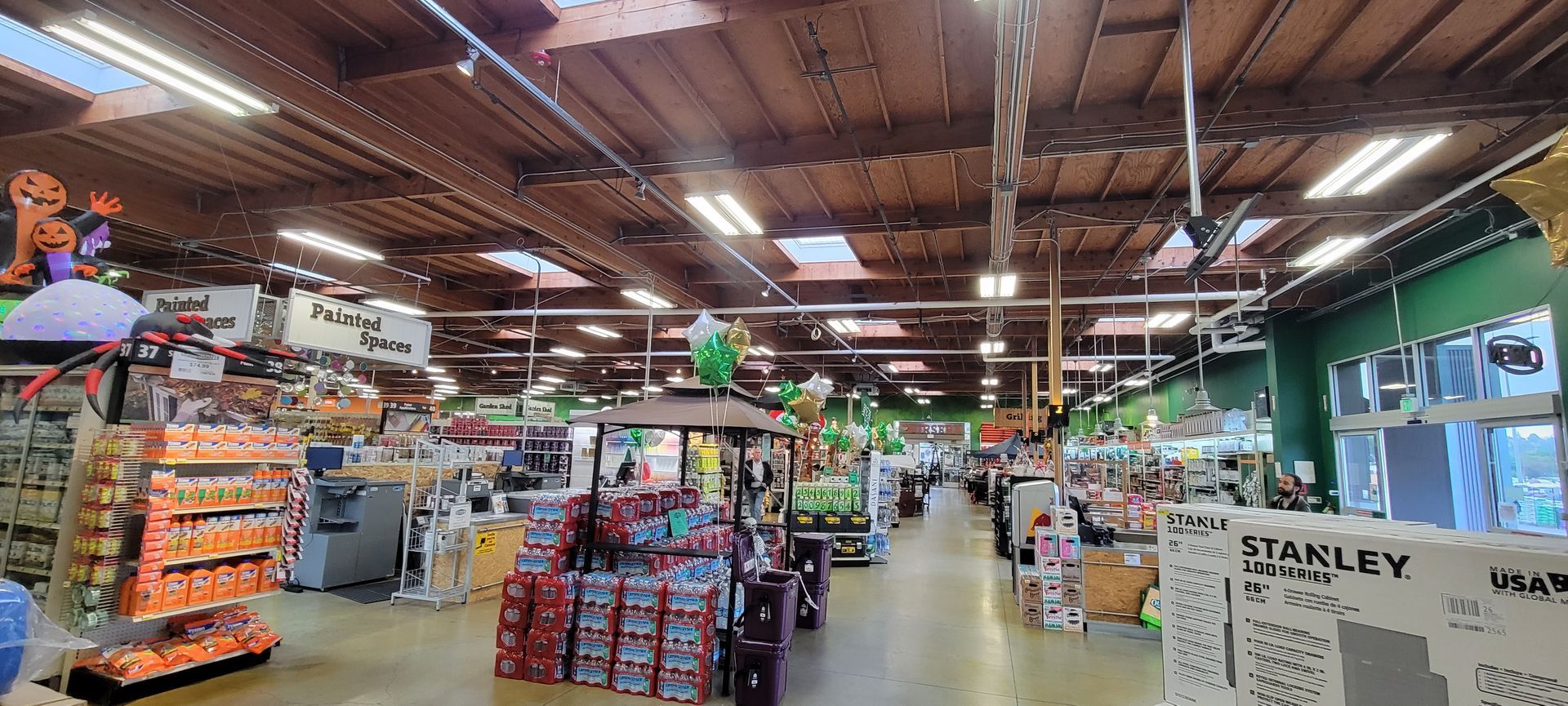 Inside a hardware store, aisles of tools and supplies under bright ceiling lights.
