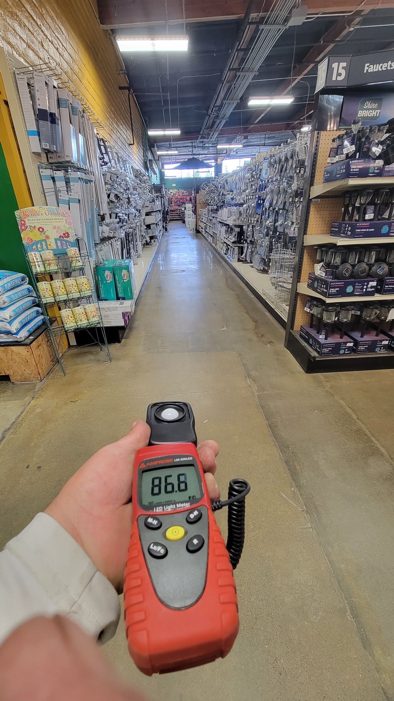 Hand holding a red device in a store aisle lined with merchandise shelves