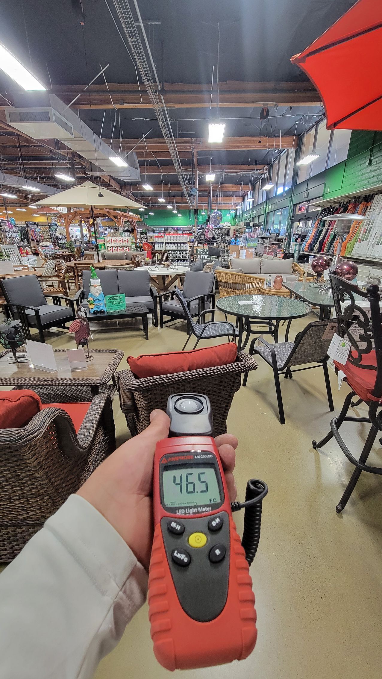 Handheld meter in a busy indoor market or food court with tables, chairs, and umbrellas.