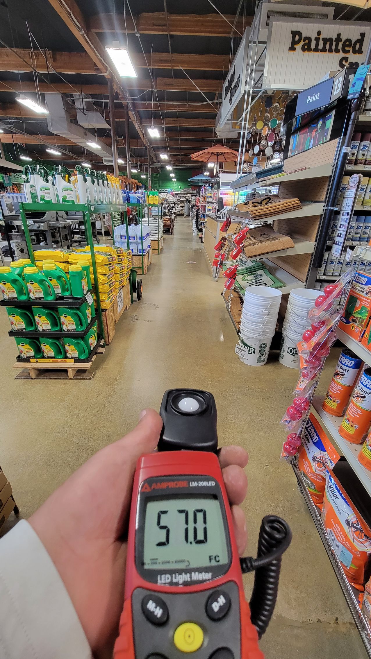 Handheld meter reading 57.0 in a grocery store aisle with shelves of snacks on both sides