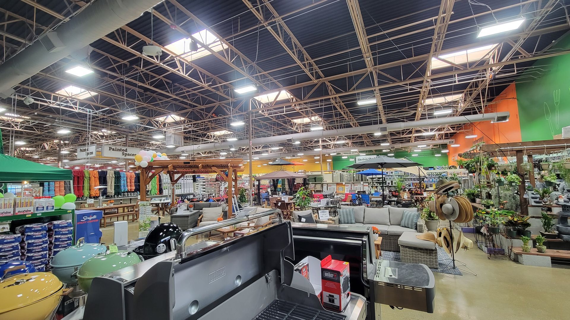 Bright indoor garden center with plants, shelves, and a high grid ceiling under skylights