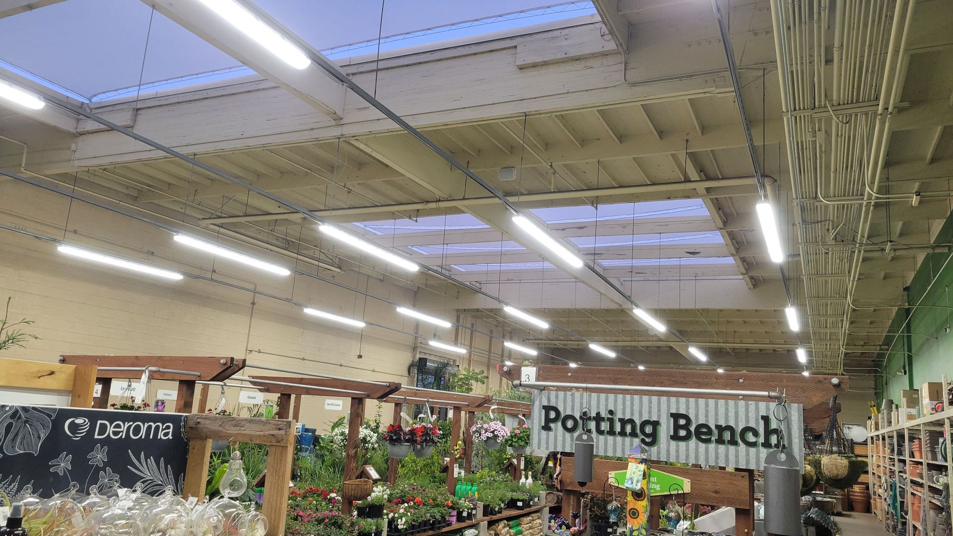 Garden center aisle with potting bench sign and plants under bright ceiling lights