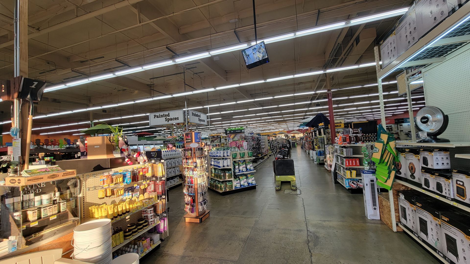 Wide grocery store aisle with shelves of household goods and bright overhead lights