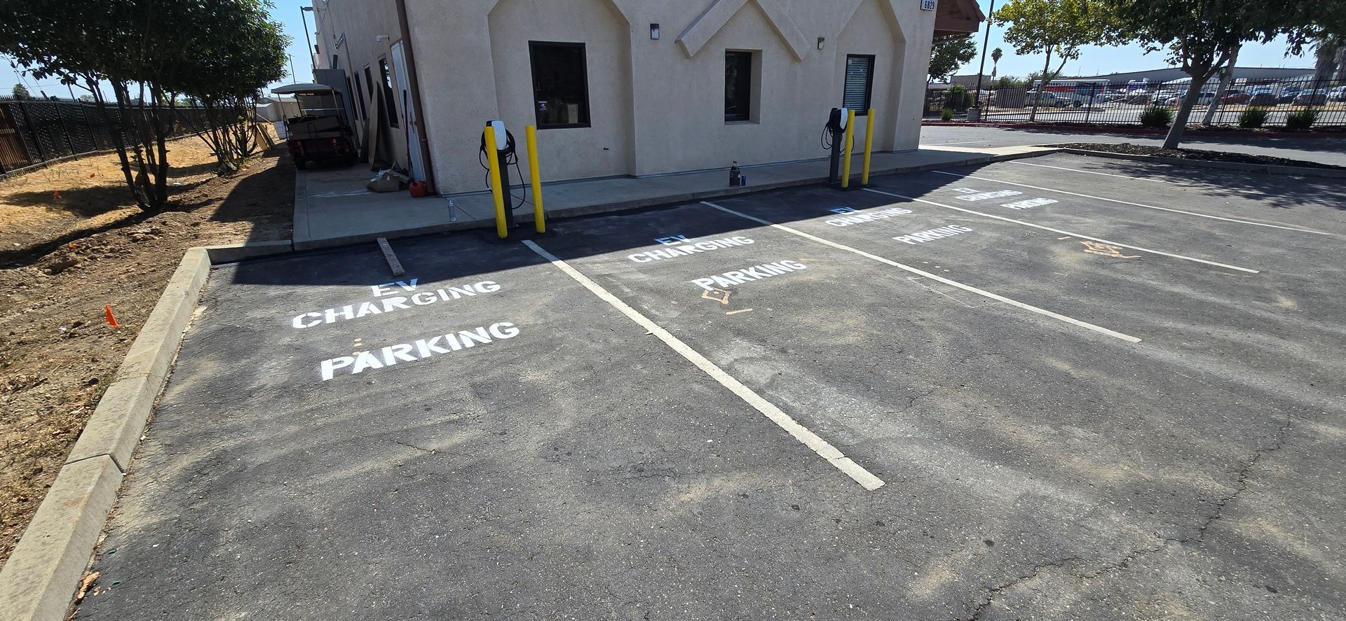 Empty parking lot beside a small white building with accessible spaces marked in white paint.