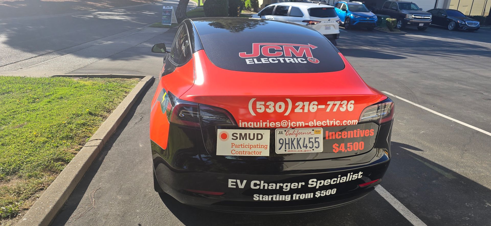 Red emergency response vehicle with company decals and phone number parked on a street curb.