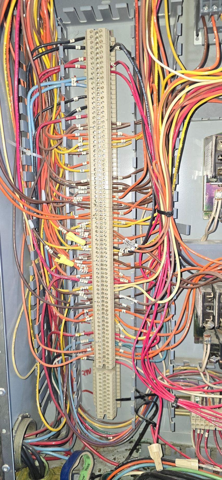 Dense bundle of red, yellow, and gray cables organized around a vertical electrical control panel.